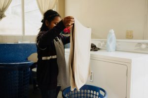 Folding clean laundry beside a home washer and dryer